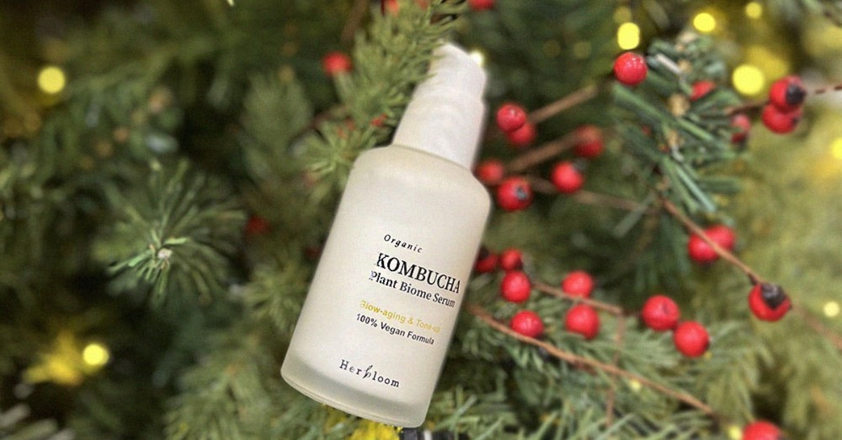 Herbloom: Bloom Into Radiance with Nature-Inspired Beauty! Kombucha serum in front of festive background.