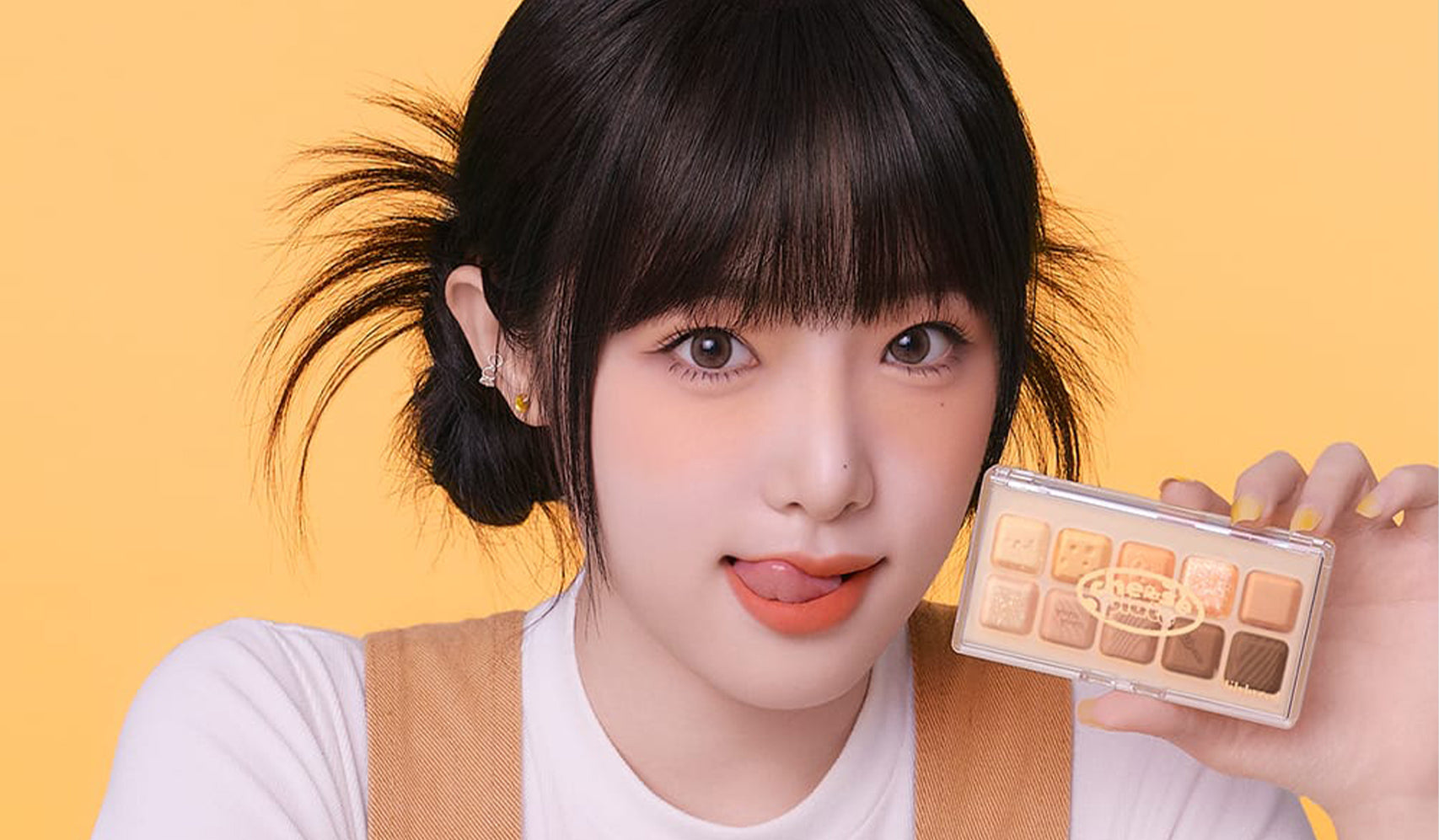 Experience Beauty Beyond Skin with LILYBRYED Cosmetics as a model showcases an eyeshadow palette against a vibrant background.