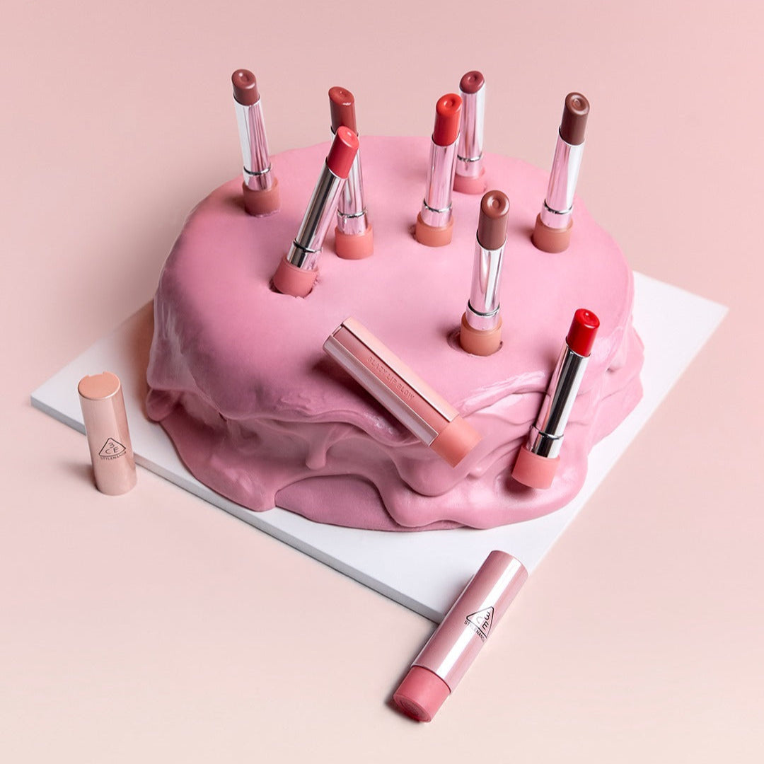 Collection of 3CE Glaze Lip Glow 3.2g lipsticks in various shades arranged creatively on a pink frosted cake.