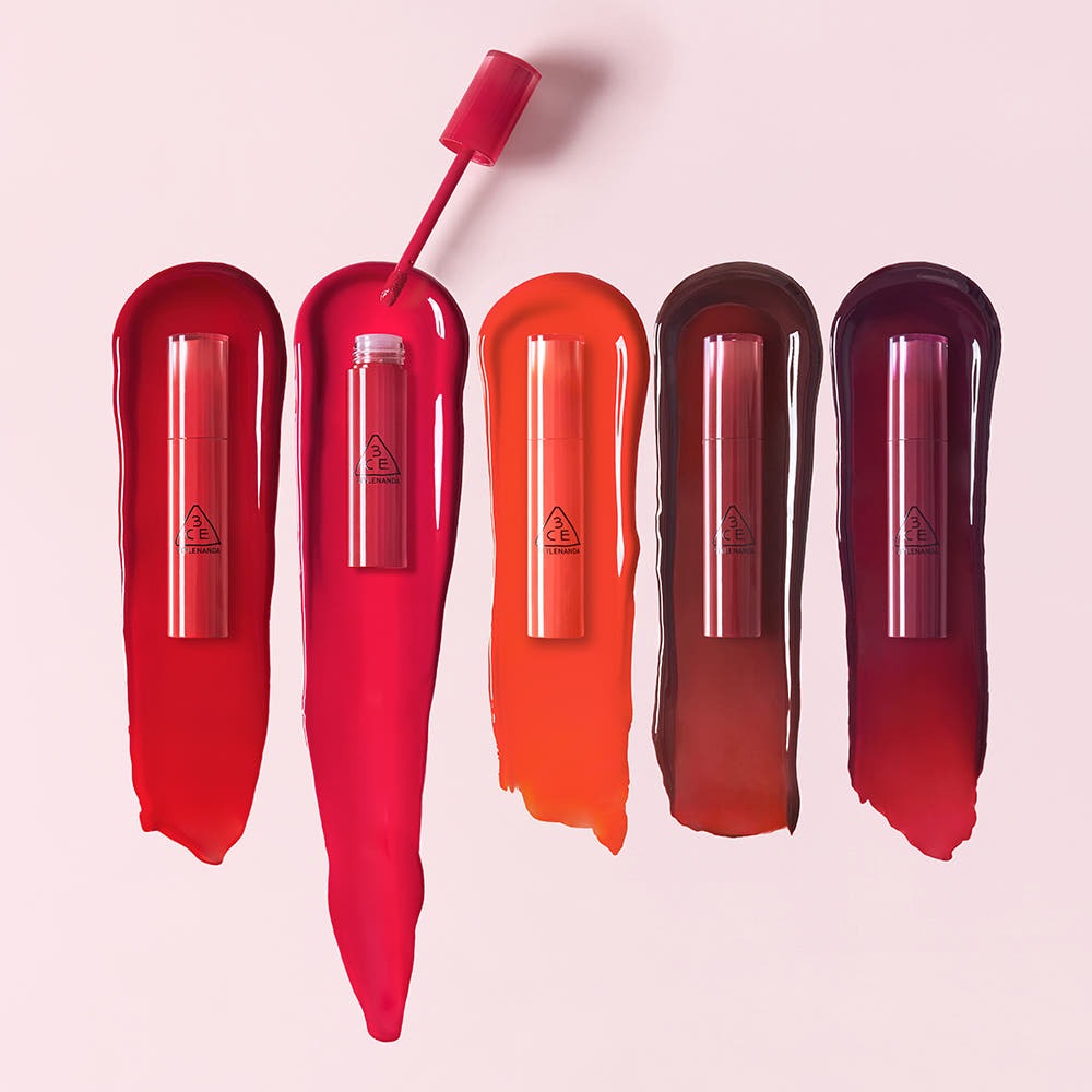 3CE Lazy Pop Lip Stain in various vibrant colors displayed on a light pink background.