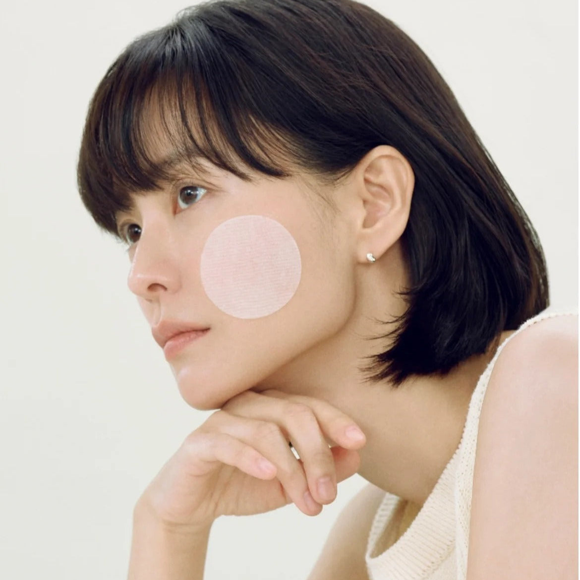 Woman using ABIB Heartleaf Spot Pad Calming Touch 70 pads on her face for soothing skincare treatment.