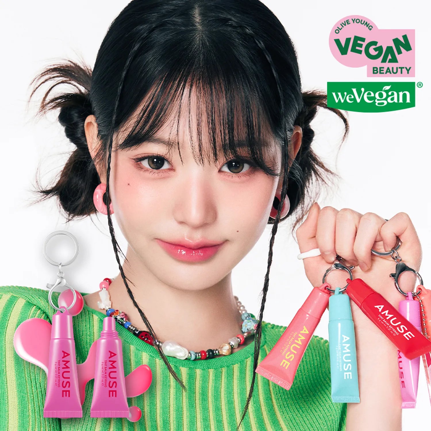 Person holding AMUSE TINT BALM KEYRING with vegan beauty labels in background.