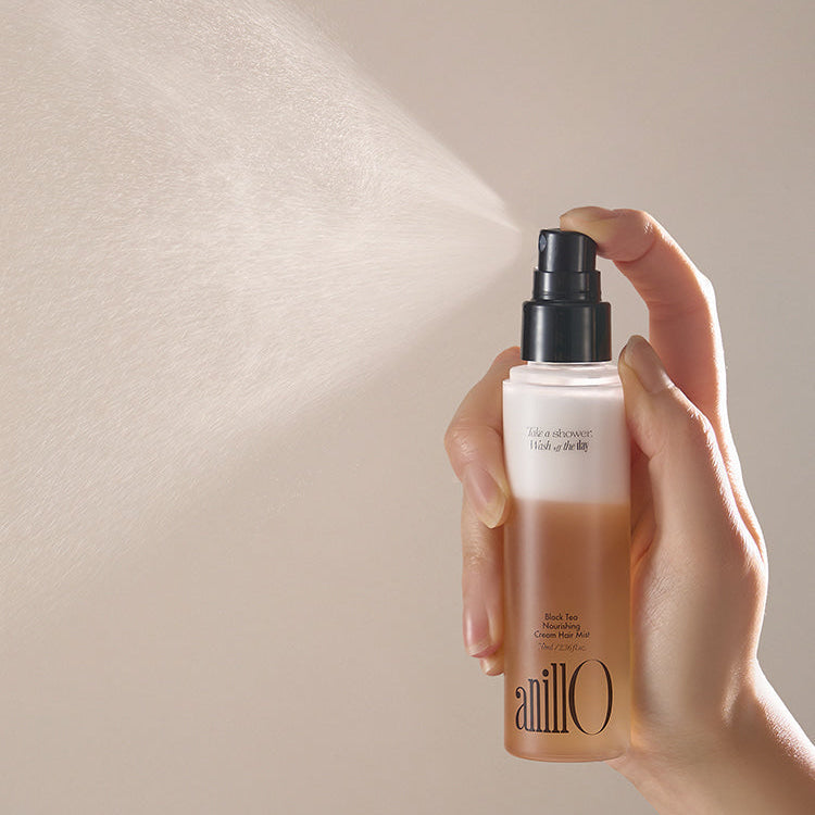 Hand holding ANILLO Black Tea Nourishing Cream Hair Mist 70ml being sprayed