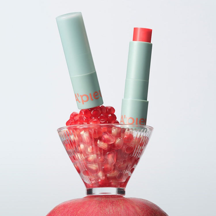 A'PIEU Juicy Pang Care Lip Balm in elegant packaging with rich color and nourishment displayed with pomegranate seeds.