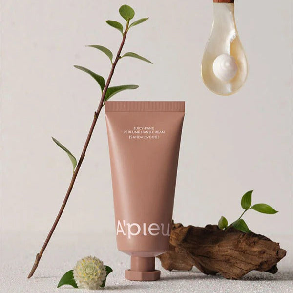 A'PIEU Juicy Pang Perfume Hand Cream 30ml with natural ingredients displayed elegantly with leaves and wood.