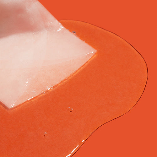 APRILSKIN Carrotent IPMP Calming & Hydrating Sheets Mask with orange essence shown on a vibrant background, highlighting product texture.