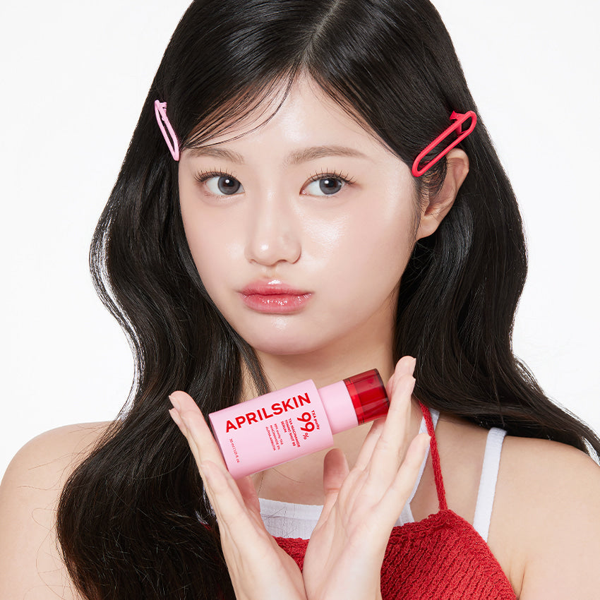 Model holding APRILSKIN TXA Niacinamide Toning Shot 99 Serum 30ml with long hair and hair clips.