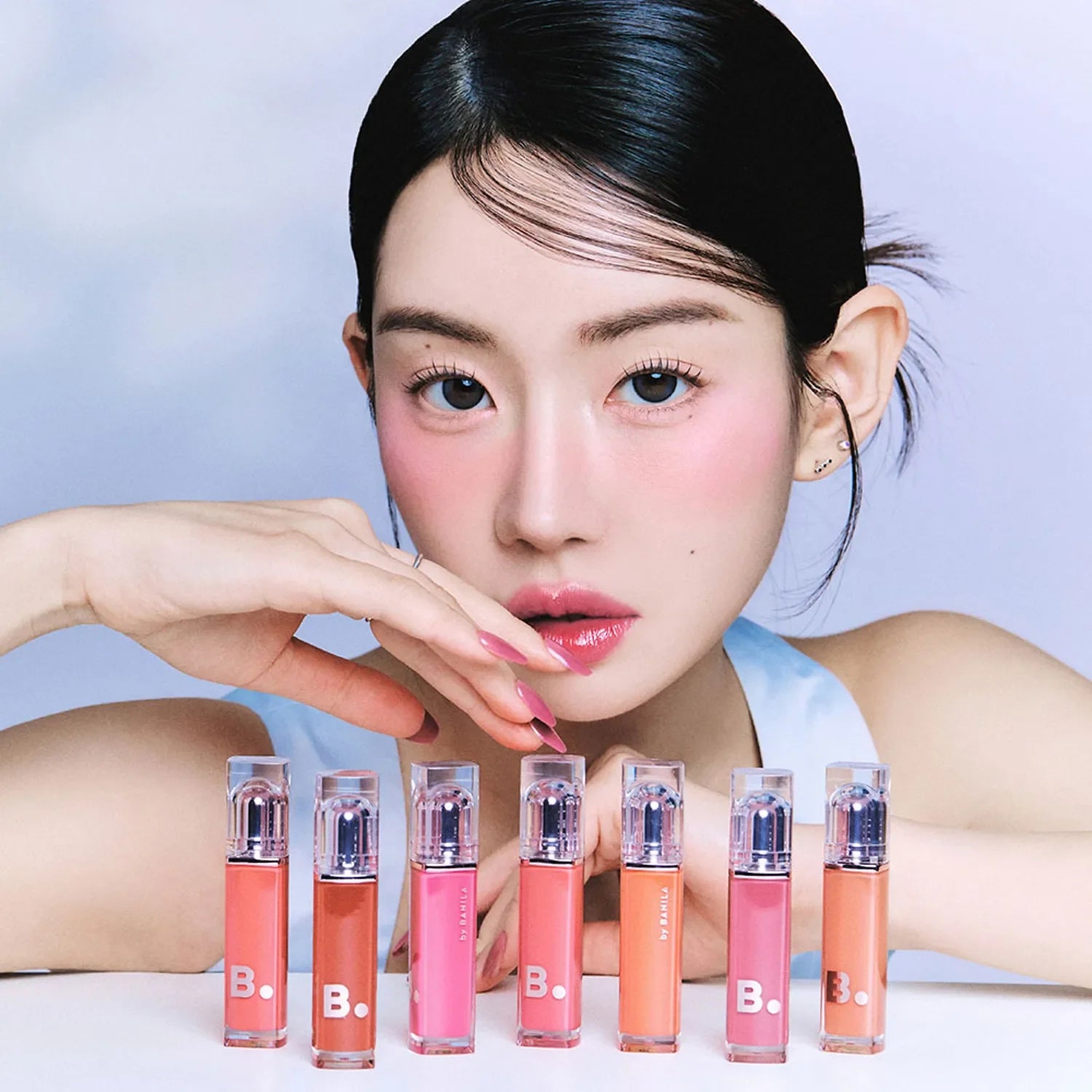 Model showcasing BANILA CO Dew Glow Tint in a variety of vibrant shades, highlighting the product's sleek packaging and color options.