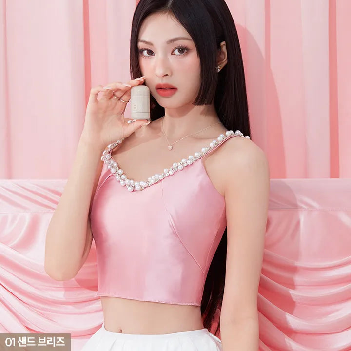 Model holding BANILA CO Romantic Blush Contour with pink satin backdrop, showcasing elegant makeup product.