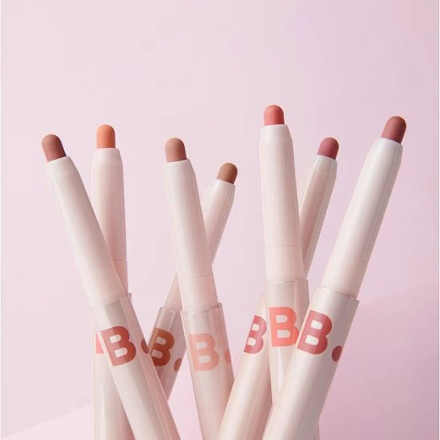 Assorted BANILA CO Smudging Lip Pencil shades displayed on pink background.