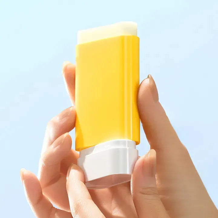Person holding BANILACO UV Defense Waterproof Sun Stick SP50+ PA++++ against a blue background.