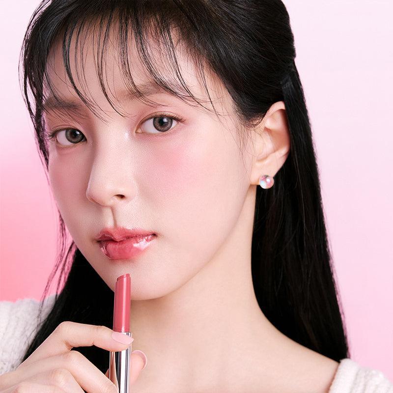 Person applying BBIA Over Glaze Stick on lips with soft pink background