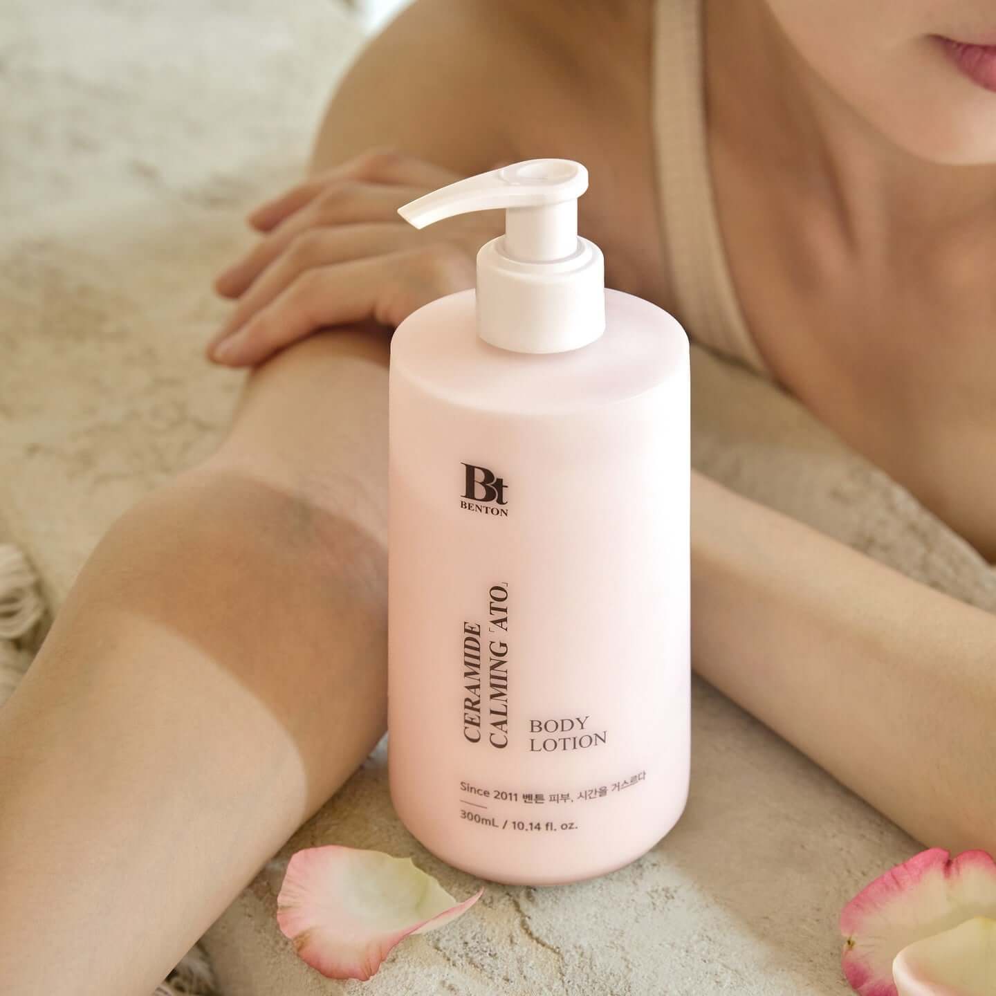BENTON Ceramide Calming Ato Body Lotion 300ml bottle on table with person relaxing nearby