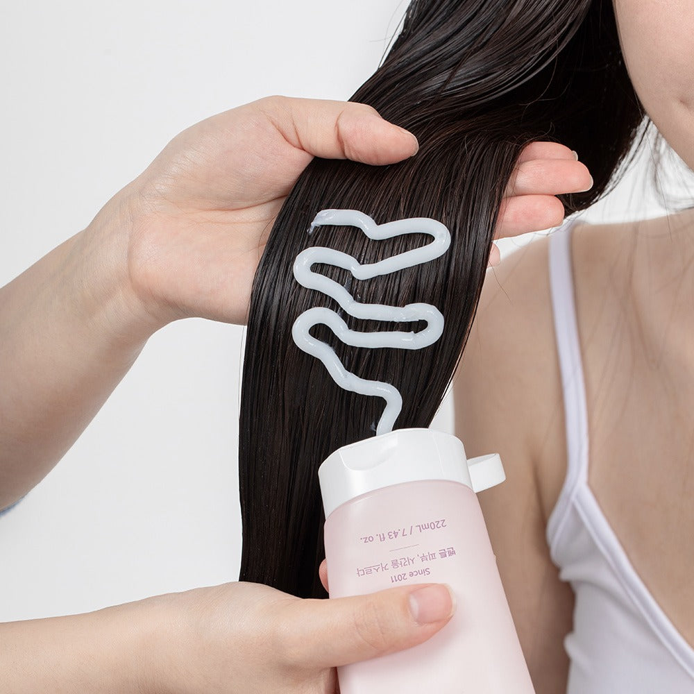 Applying BENTON Glycine Protein Deep Conditioning Hair Mask 220ml to dark hair for nourishment and shine.
