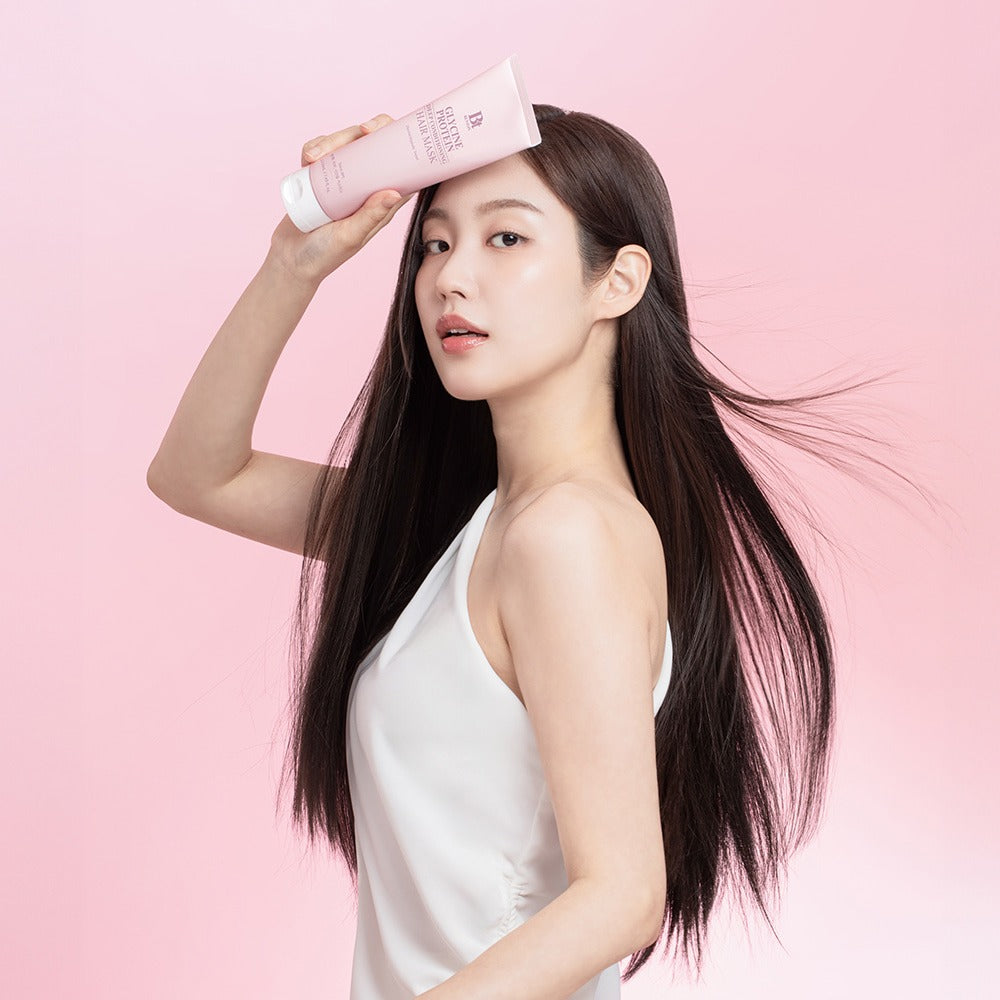 Woman holding BENTON Glycine Protein Deep Conditioning Hair Mask 220ml on a pink background, showcasing smooth and shiny hair