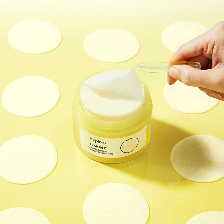 BEPLAIN Lemon Seed Glutathione Whitenning Pads 70 Sheets in a jar with a hand lifting one pad on a yellow background
