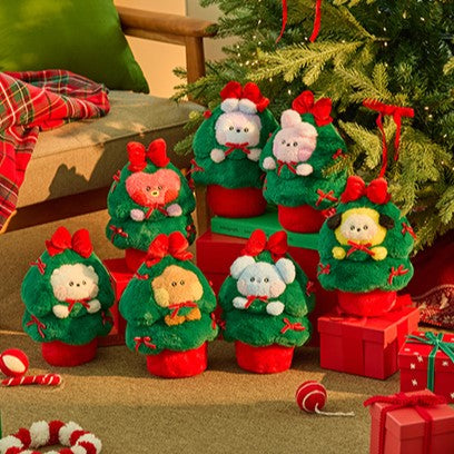 BT21 Minini Petit Holiday Tree Plushy en peluches festives devant un sapin de Noël décoré et cadeaux rouge. Peluches BT21 Minini.