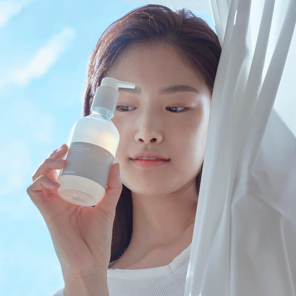 Woman holding CELIMAX Dual Barrier Mild Gel Cleanser 200ml by a window.