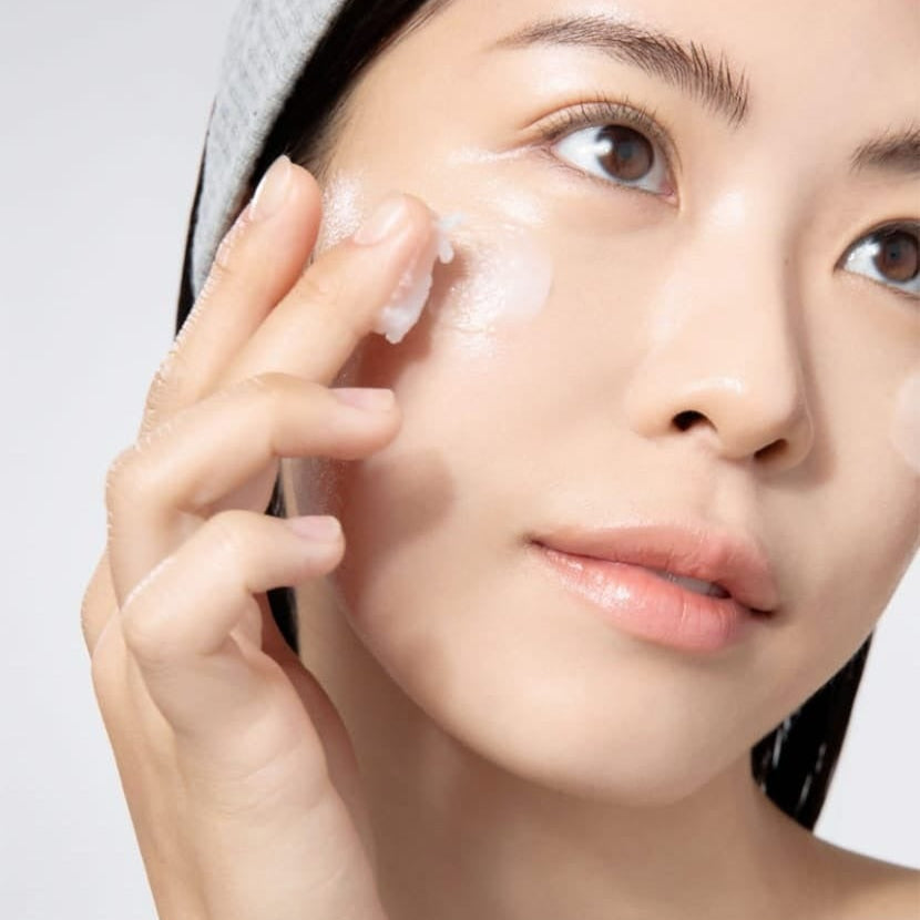Woman applying skin care product on face