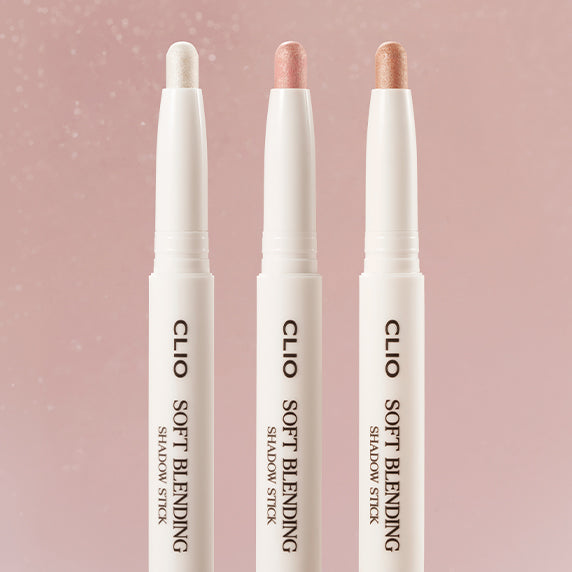 Three CLIO Soft Blending Shadow Sticks in pastel shades on a pink background, showcasing smooth texture and easy application.
