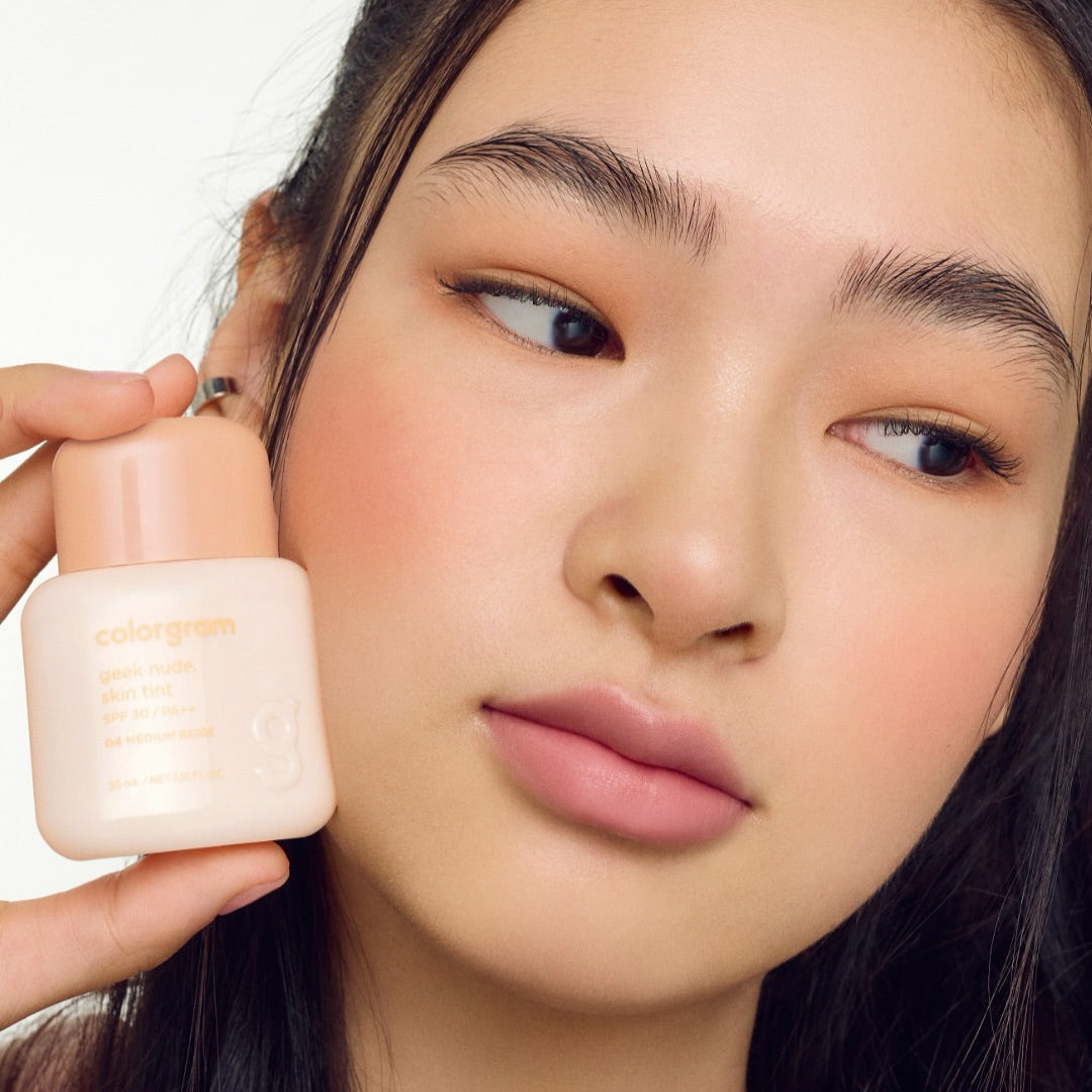 Person holding a bottle of COLORGRAM Geek Nude SKin Tint 30ml against skin.