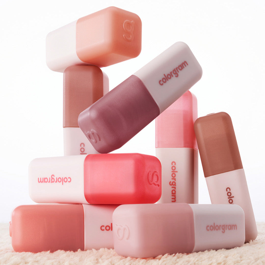 Various shades of COLORGRAM Nude Blur Tint lipsticks stacked artistically showcasing the product's variety and branding.
