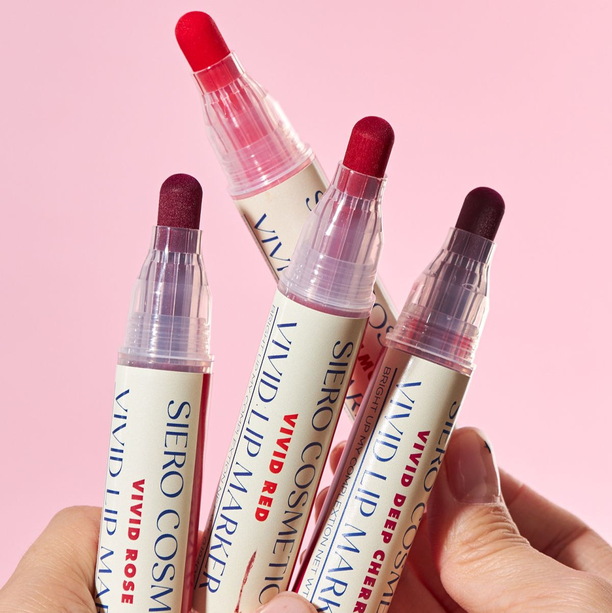 COSIERO Vivid Lip Marker in four vibrant shades held against a pink background.