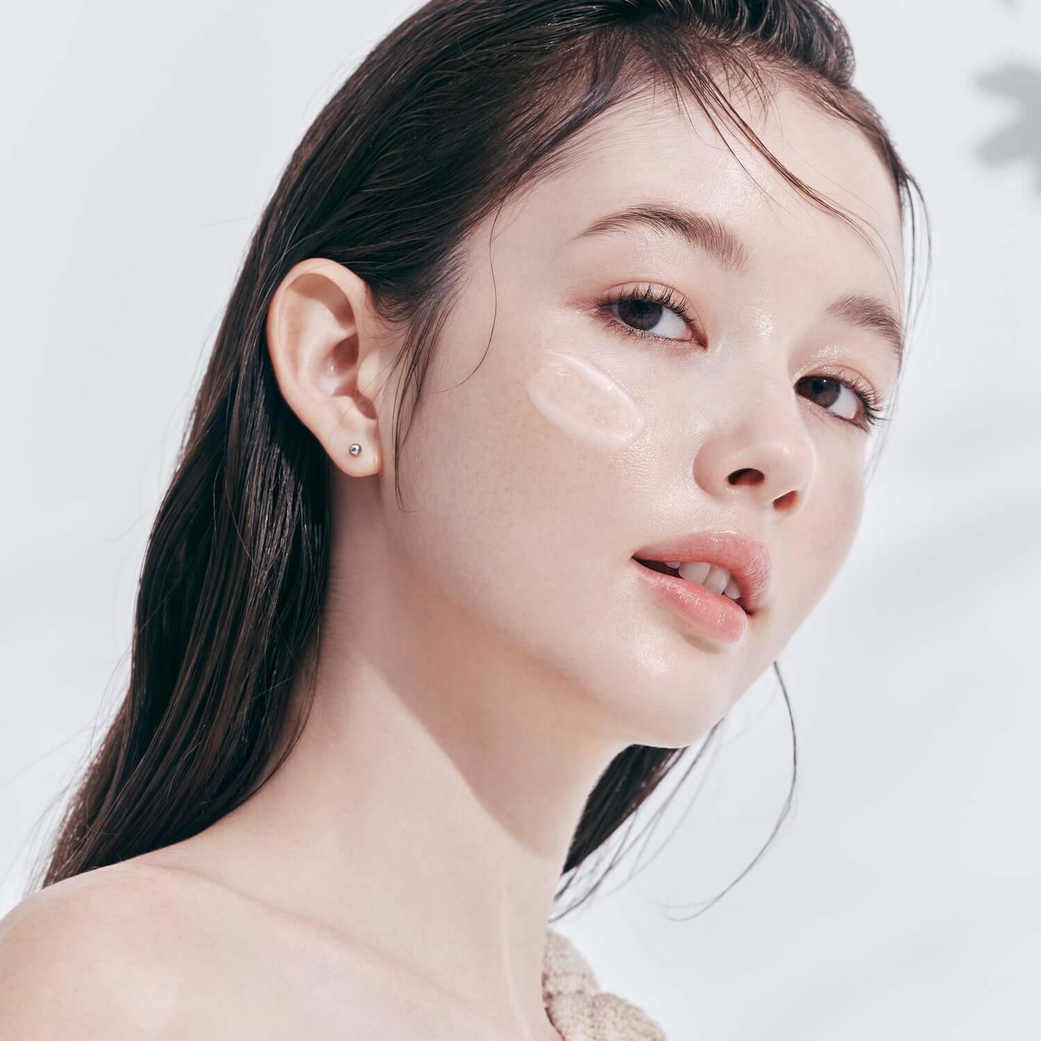 Model applying DEAR DAHLIA Prime Layer Skin Prep on cheek for smooth, radiant finish.