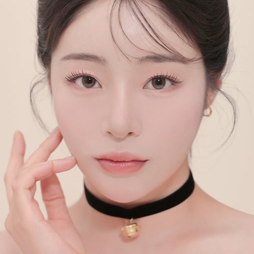 Model wearing subtle makeup with soft focus, showcasing natural beauty and neutral tones.