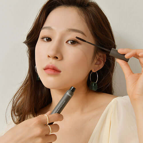 Woman applying mascara with DINTO Dante Lash Definer for defined lashes.