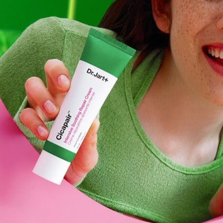 Person holding DR.JART+ Cicapair Intensive Soothing Repair Cream 50ml tube with green and pink background.