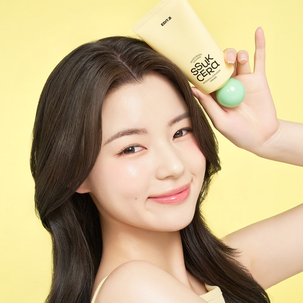 Smiling person holding EDIT.B Moisturizing Soothing Mugwort Ceramide Cream 100ml against a yellow background.