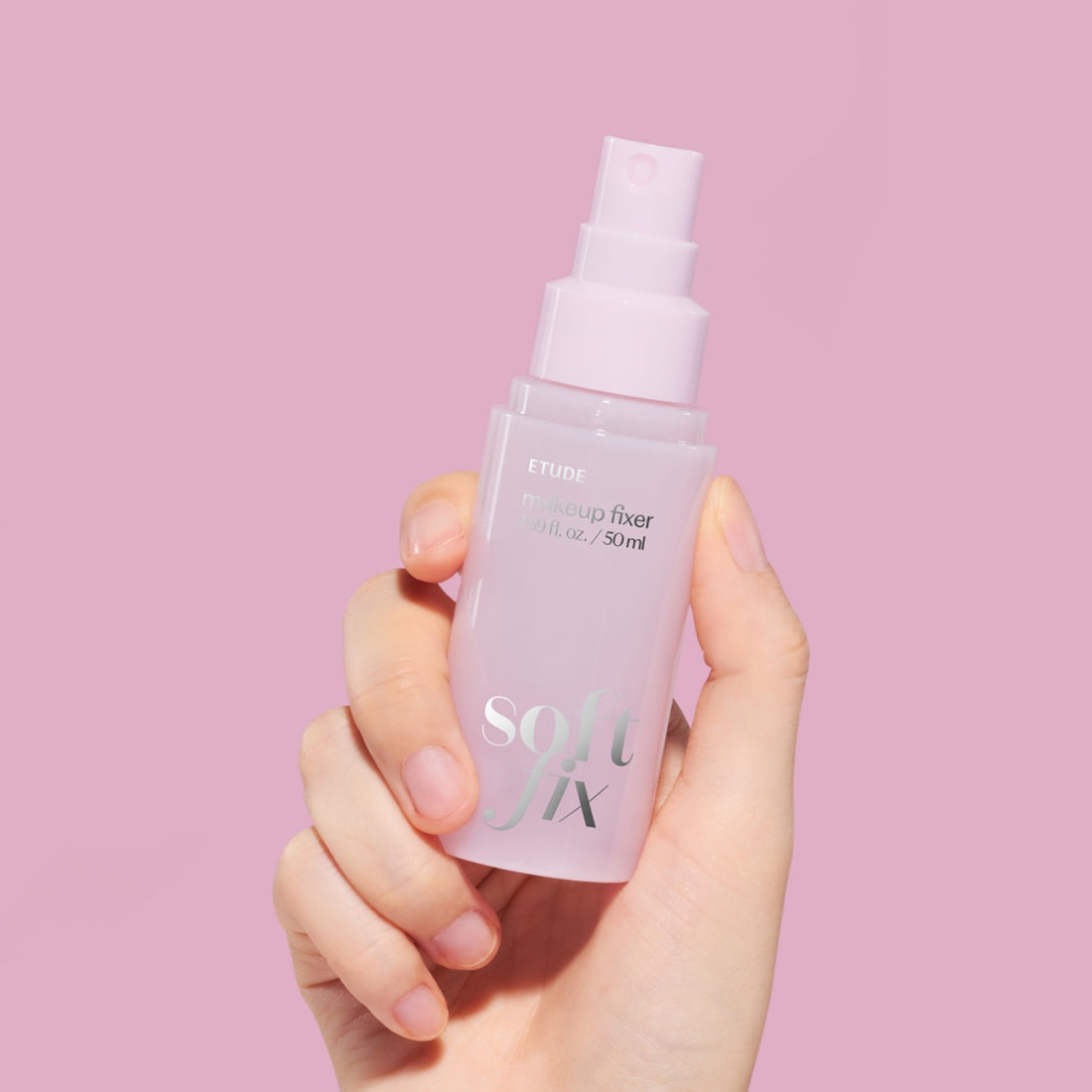 Hand holding ETUDE Soft Fix Makeup Fixer 50ml against pink background