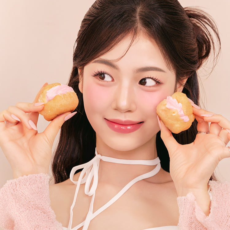 Woman with pink blush holding pastries, wearing FORENCOS Soft Fitting Cream Blusher, demonstrating makeup application.