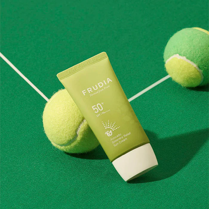FRUDIA Avocado Greenery Relief Sun Cream 50g tube on green surface with tennis balls