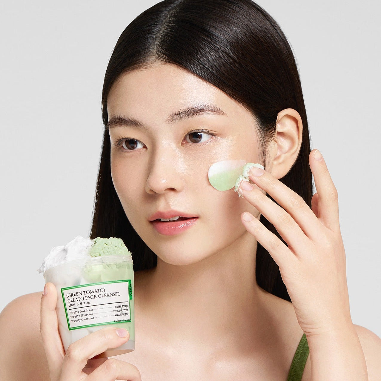 Woman applying FULLY Green Tomato Gelato Pack Cleanser 100ml on her face.