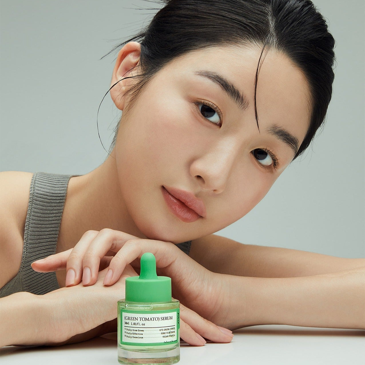 Woman with FULLY Green Tomato Serum 30ml in front of her, showcasing beauty skincare product.