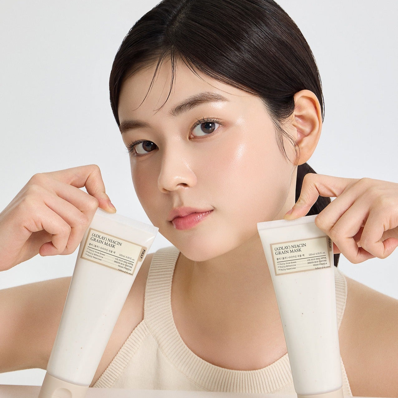 Person holding tubes of FULLY Job's tears niacin grain pack 120ml skincare product