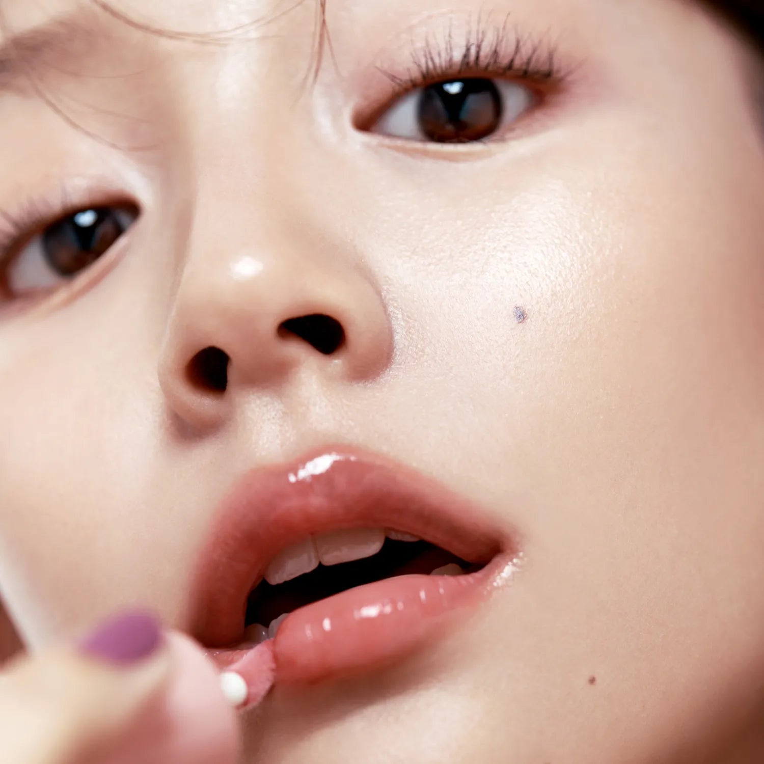 Close-up of a person applying FWEE 3D Voluming Gloss to lips for a shiny finish.