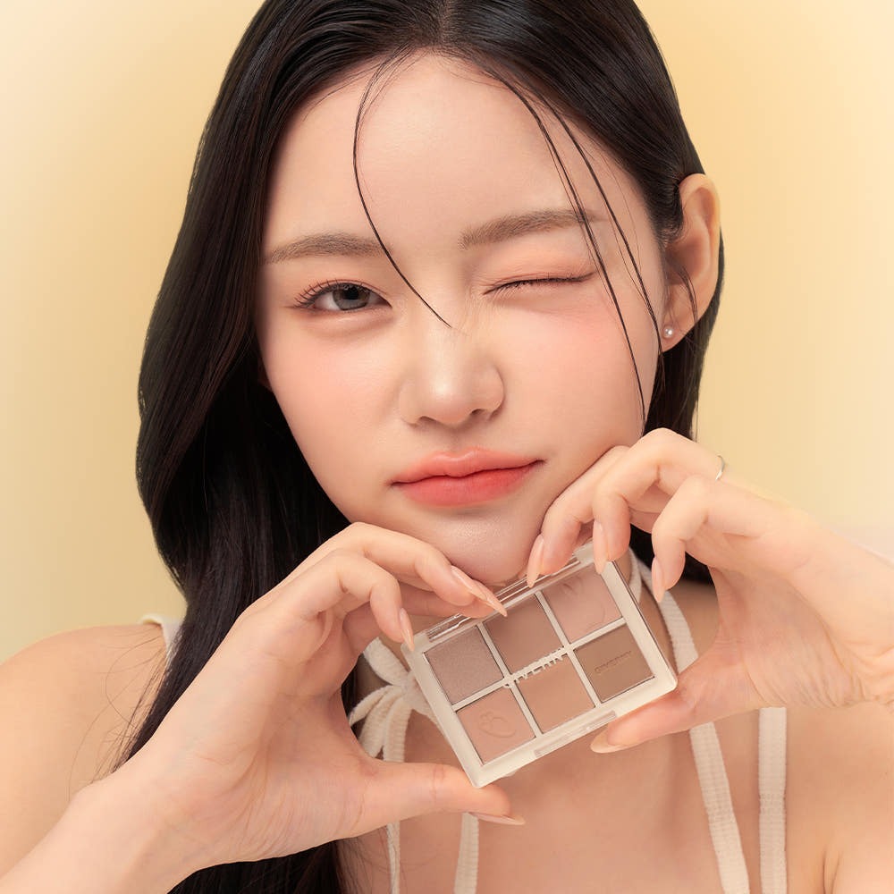 Woman holding GIVERNY Soft Eye Palette 6-Color 5g (3 Colors) near her face, displaying the eyeshadow shades.