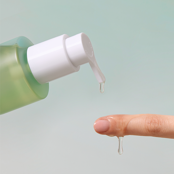 Dispensing GOODAL Eoseongcho Hyaluronic Soothing Pore Cleansing Oil 200ml onto a finger with a green background.
