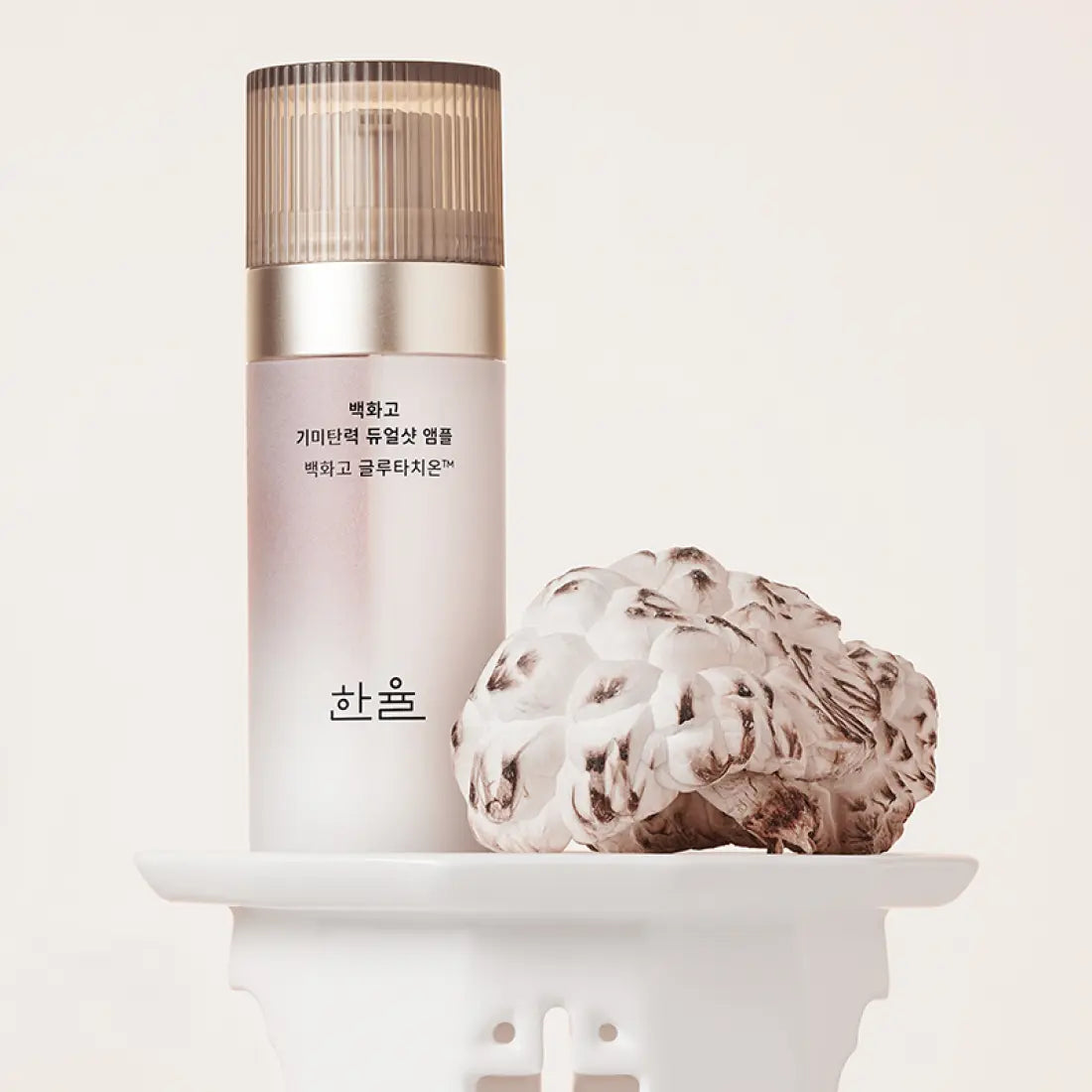 HANYUL Baekhwago Gimitanryuk Dual Shot Ampoule 45ml bottle on display with decorative plant.
