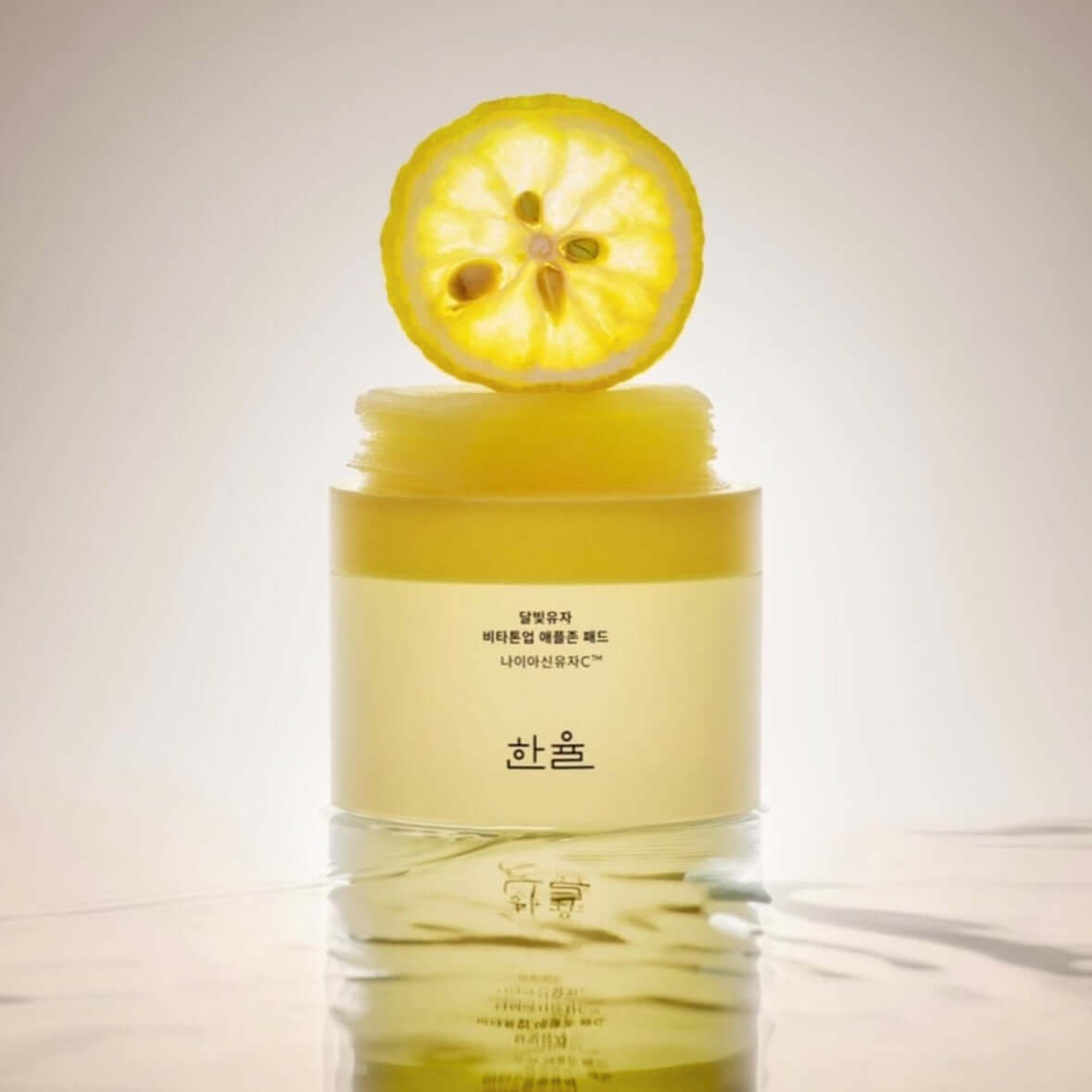 HANYUL Moonlight Yuja Vita Tone Up Apple Zone Pad with a citrus slice on top, enhancing natural skin glow and luminosity.