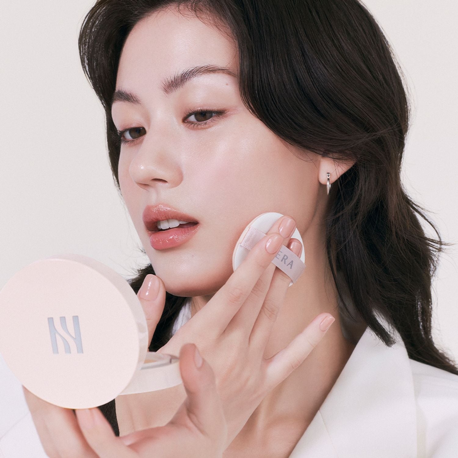 Woman applying HERA Reflection Skin Glow Cushion Foundation 15g for a radiant skin finish.