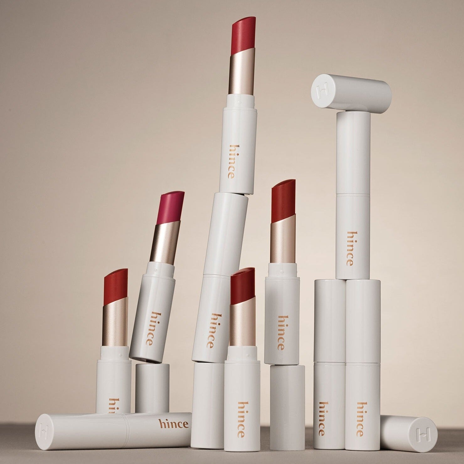 HINCE Mood Enhancer Lip Glow lipsticks in various shades, elegantly stacked with sleek packaging, showcasing vibrant color options.