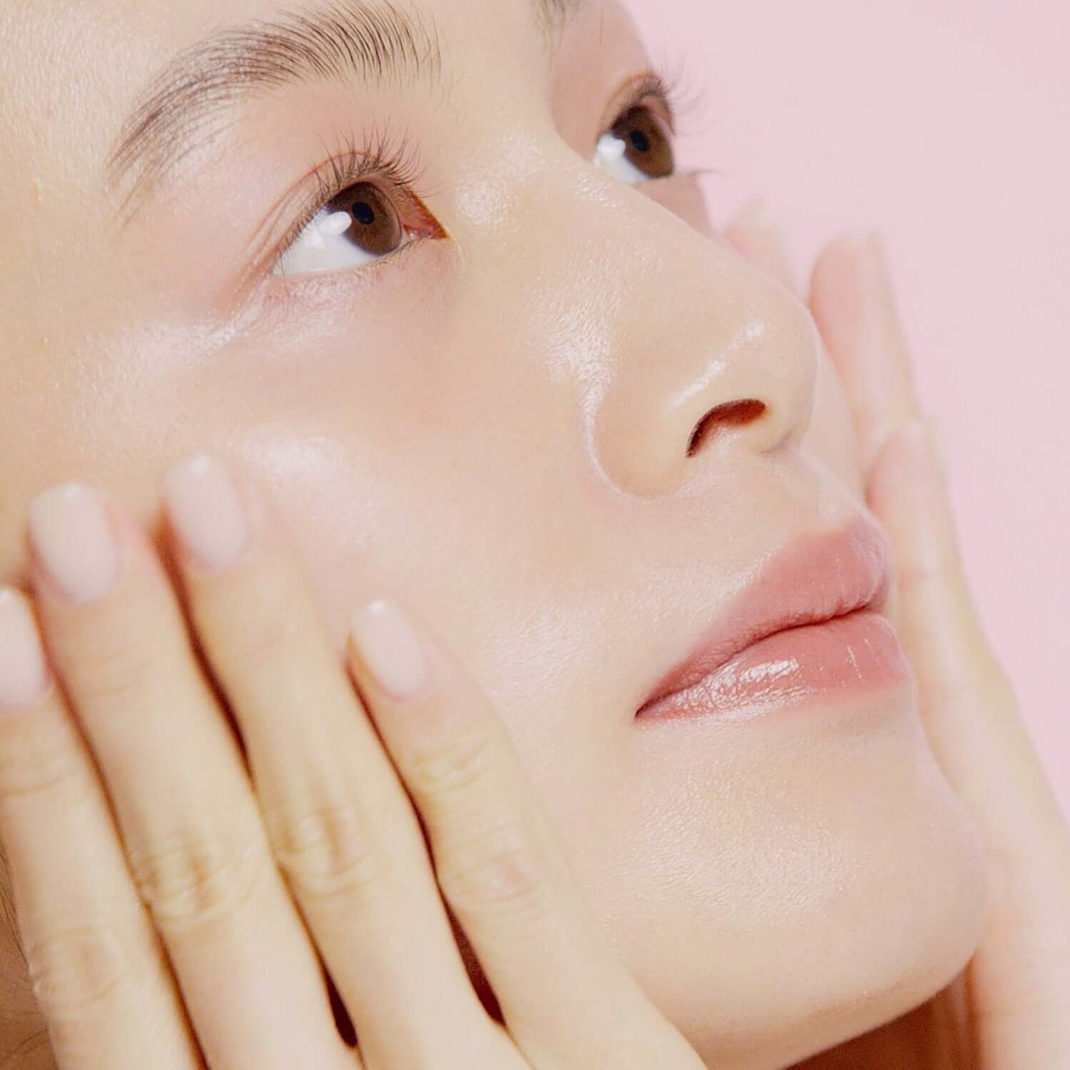 Close-up of woman applying HINCE Second Skin Hydrating Primer, showcasing radiant and hydrated skin.