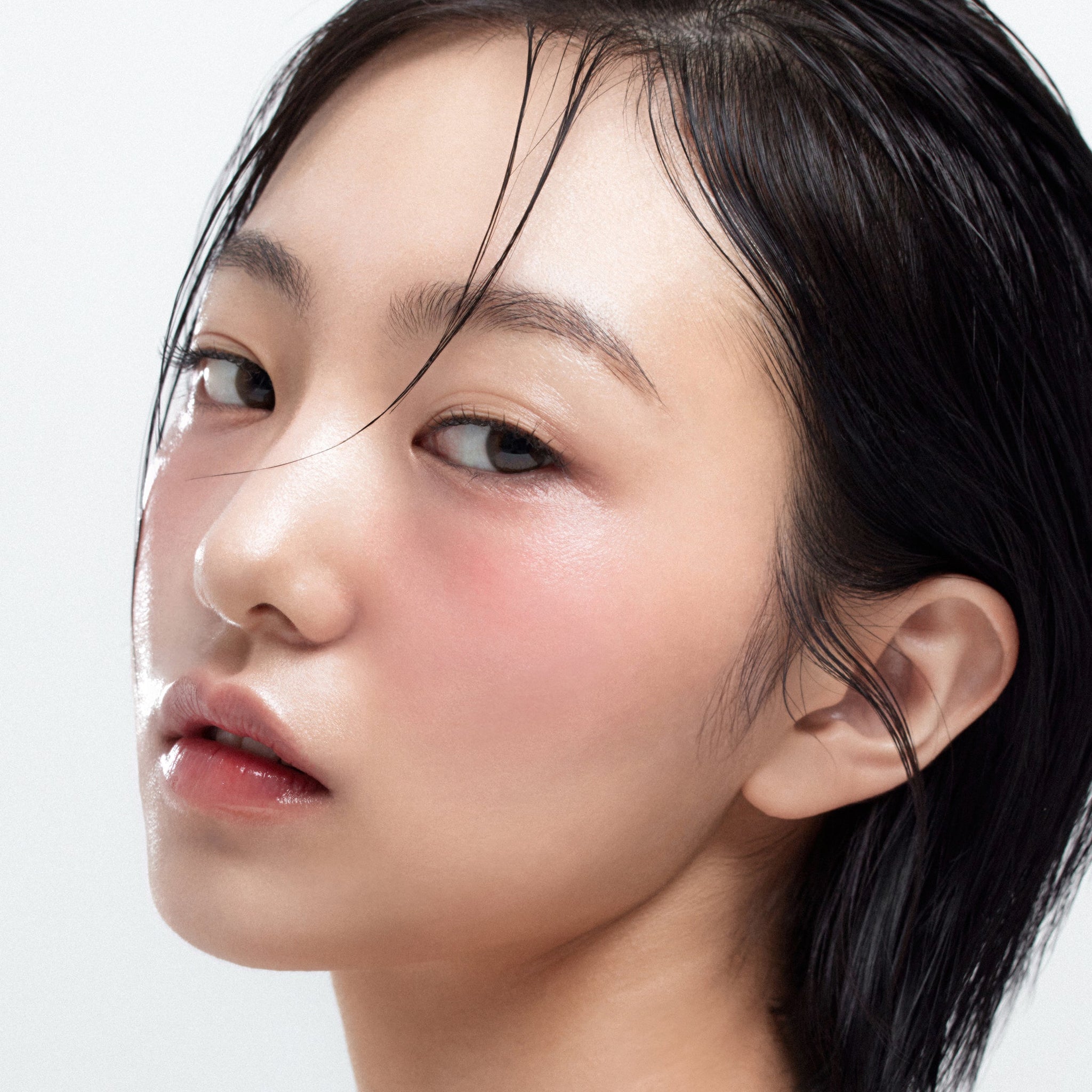 Close-up of model wearing HOUSE OF HUR Moist Ampoule Blusher 10ml on cheeks, showcasing natural glow and dewy finish.