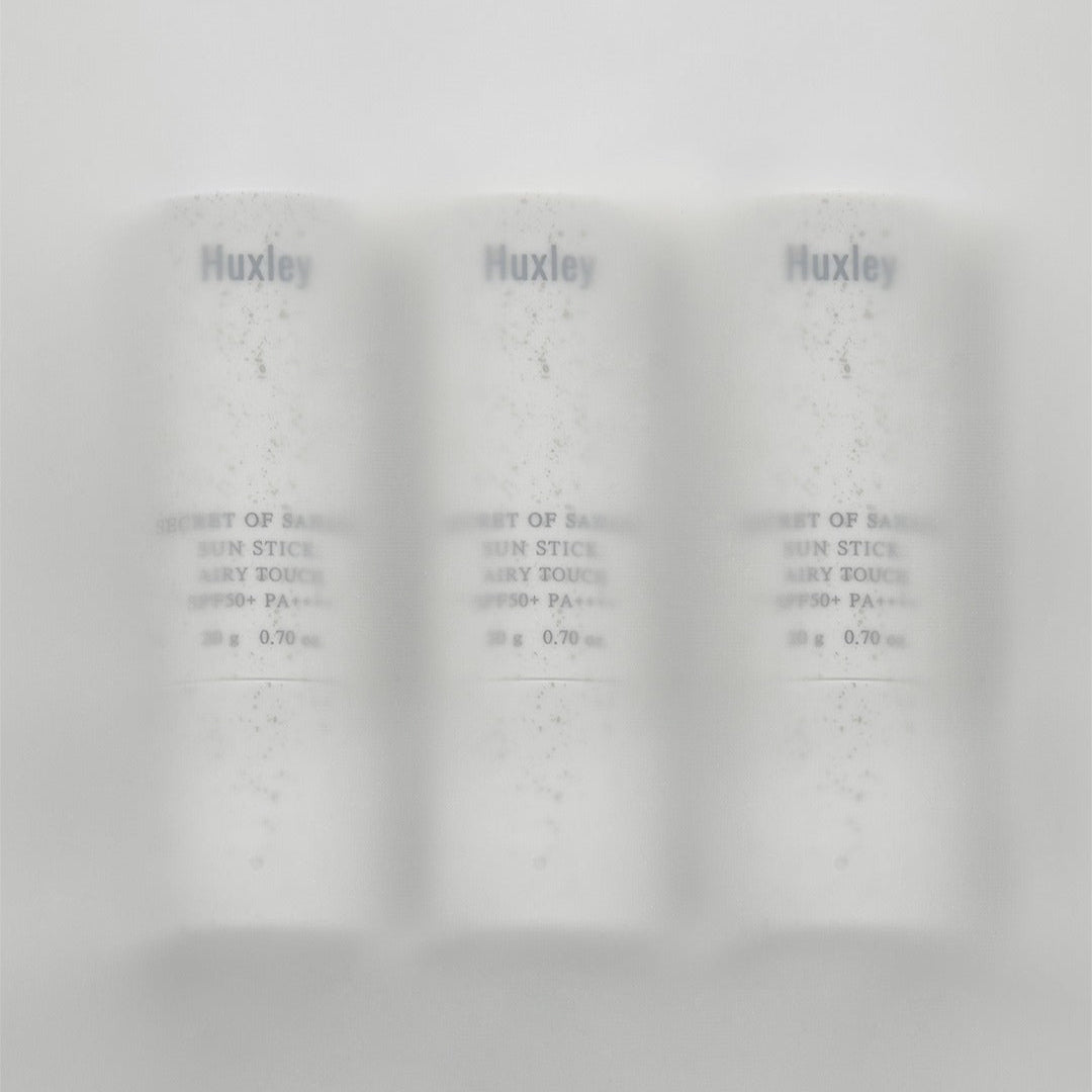 Image of HUXLEY Sun Stick Airy Touch 20g, featuring three sleek white containers in a row, emphasizing sun protection and skincare convenience.