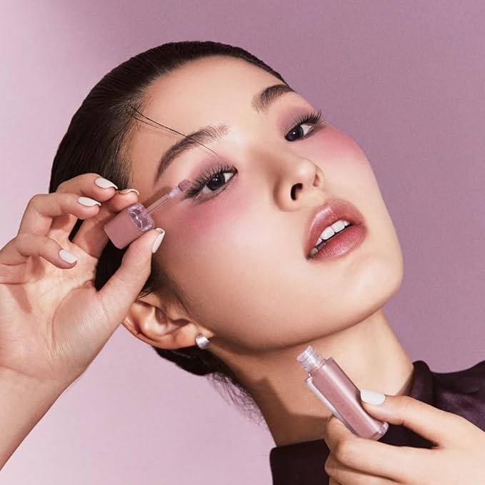 Woman applying JAVIN DE SEOUL Wink Eye Shade Primer with a pink background