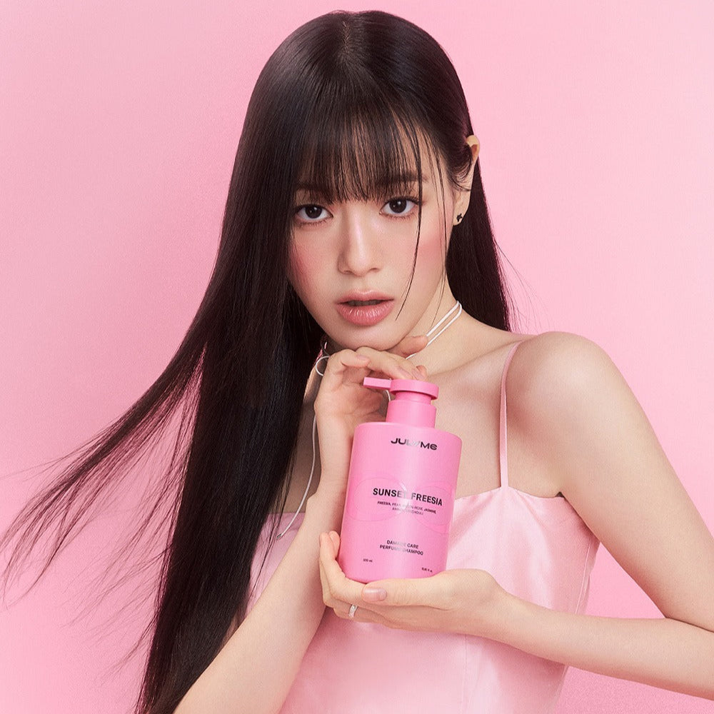 Woman holding JULYME Damage Care Perfume Hair Shampoo 500ml bottle in pink dress with pink background.